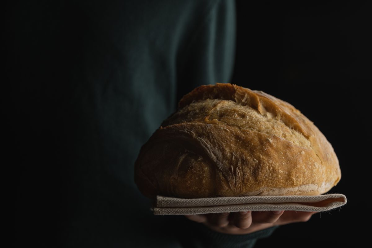 Ką tik iškeptas naminis duonos kepalas ant medinės mentės